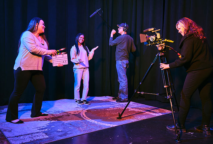 three crew members surround a person ready to record in a studio room