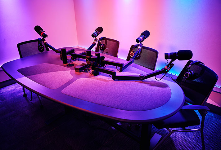an empty table in a dimly lit room with four chairs and microphones